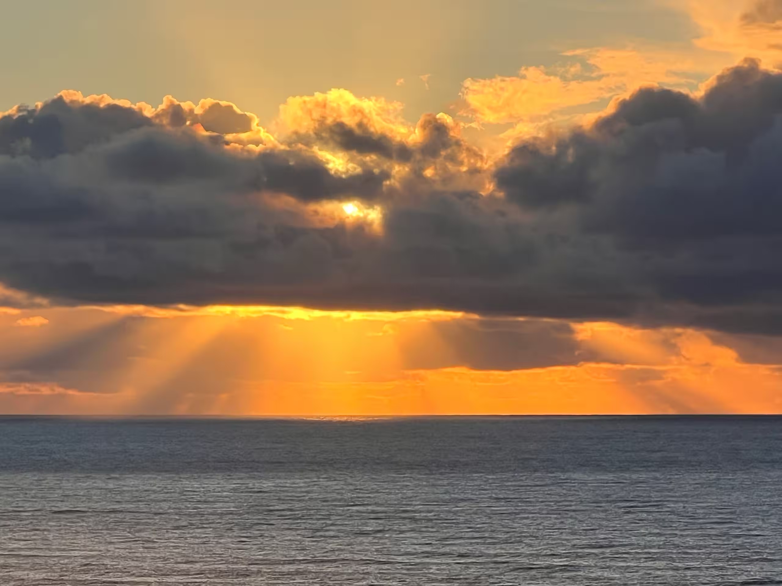 Sunset over the ocean in Smith River with golden rays bursting through dark clouds